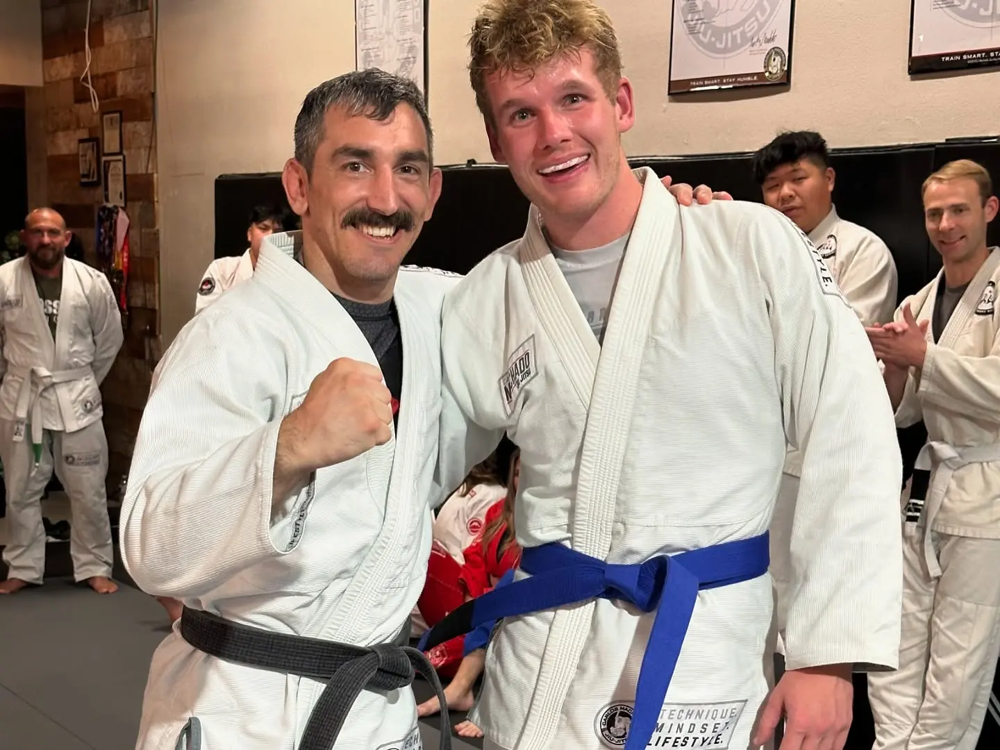 An instructor and an adult student celebrating a blue-belt promotion at 805 Combat Sports in Simi Valley