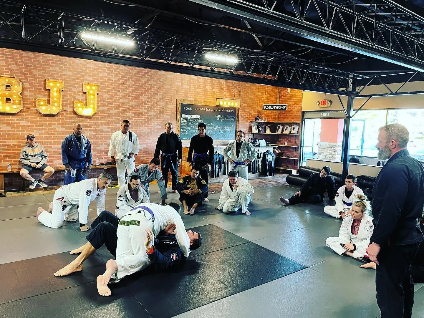 An adult class gathered around the instructor during a technique breakdown at 805 Combat Sports in Simi Valley