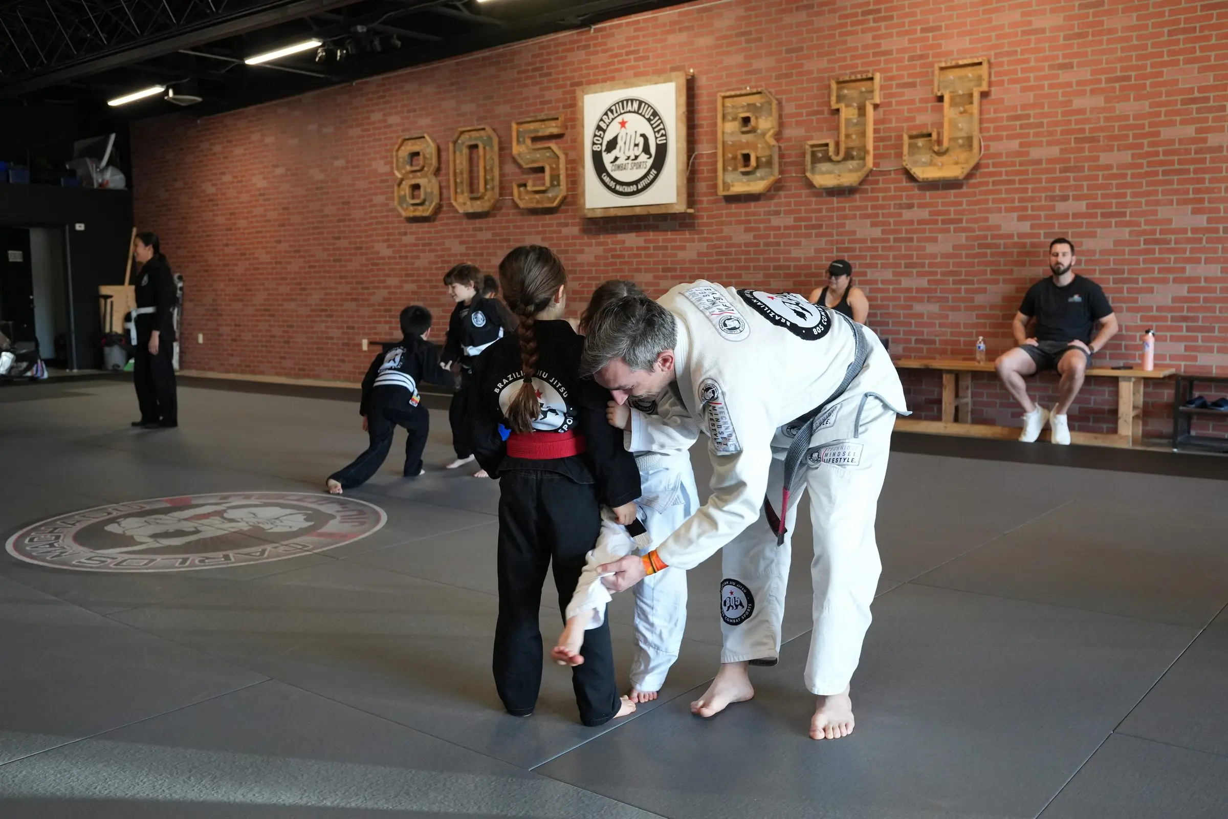 An instructor working with a young student by the 805 BJJ wall at 805 Combat Sports in Simi Valley
