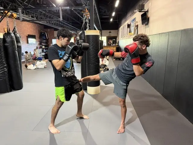 A student landing a kick on the heavy bag during Muay Thai training at 805 Combat Sports in Simi Valley